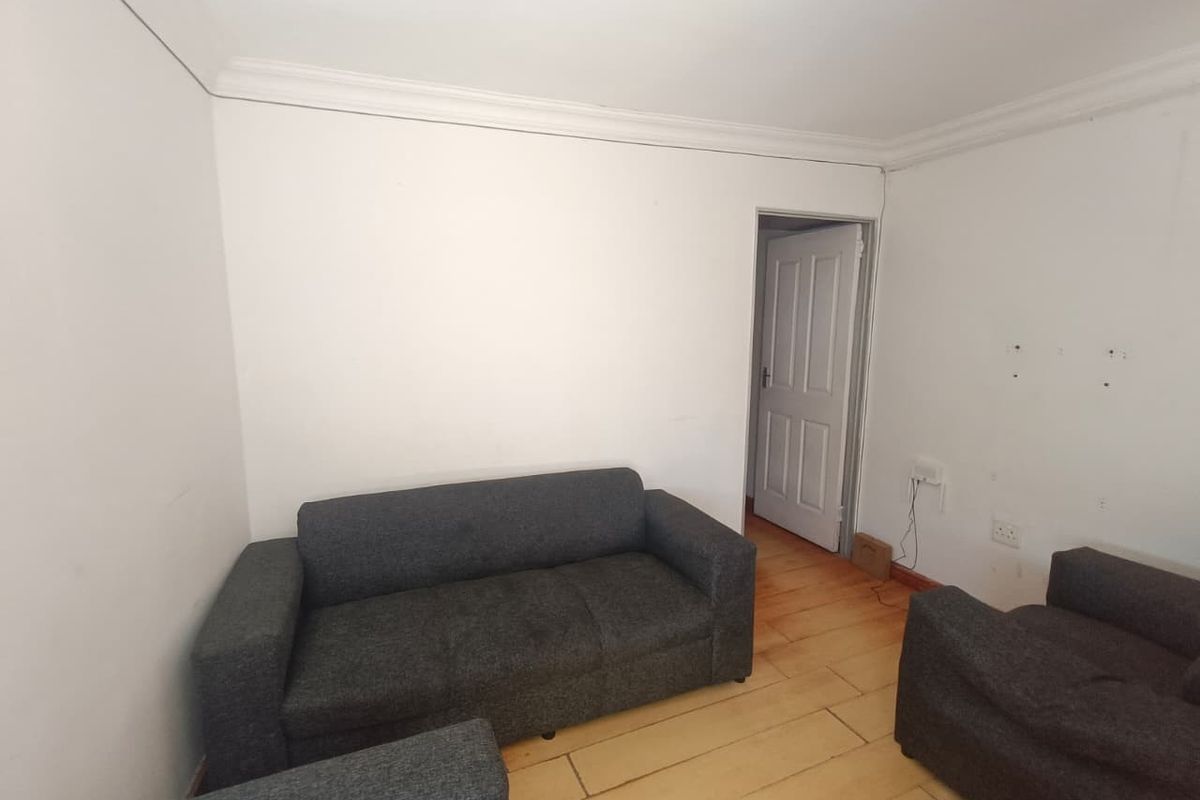 A living room featuring timber flooring, coving, and neutral walls, currently requiring cosmetic updates to improve its overall condition and appeal.
