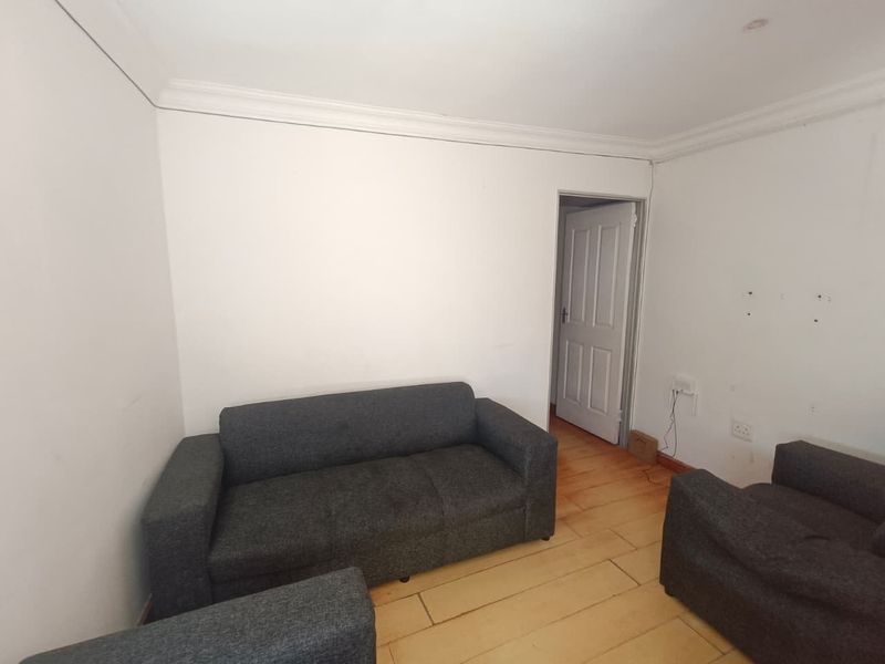 A living room featuring timber flooring, coving, and neutral walls, currently requiring cosmetic updates to improve its overall condition and appeal.