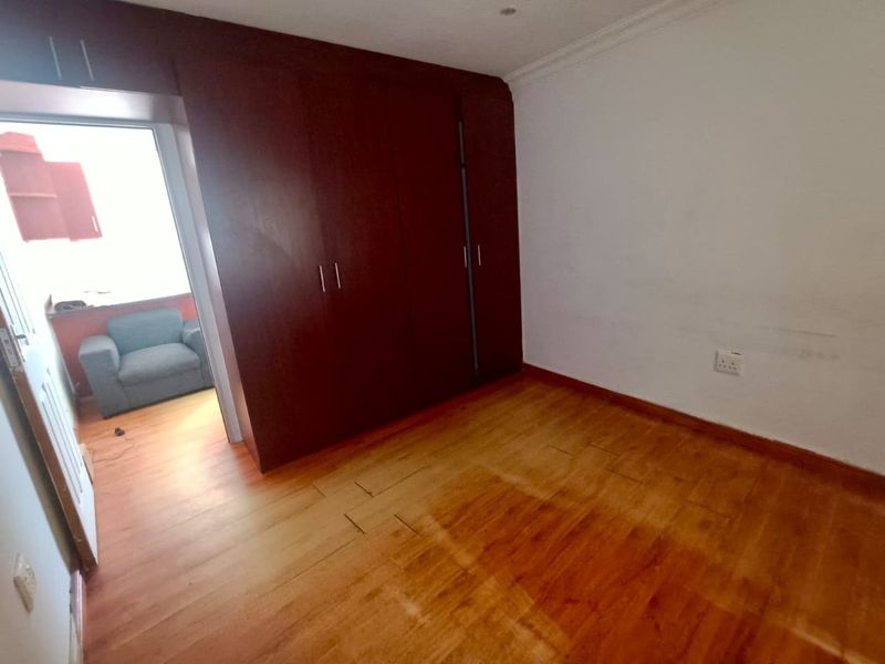 An empty bedroom featuring dark wood built-in cupboards and laminate flooring, offering a blank canvas for personalization.