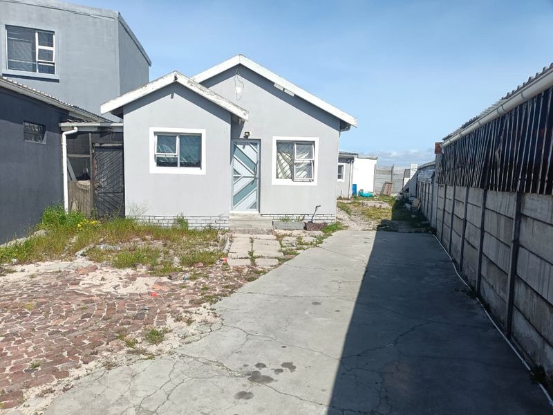 Front view of a detached house featuring a concrete driveway, security features, and a yard area requiring landscaping and exterior maintenance.
