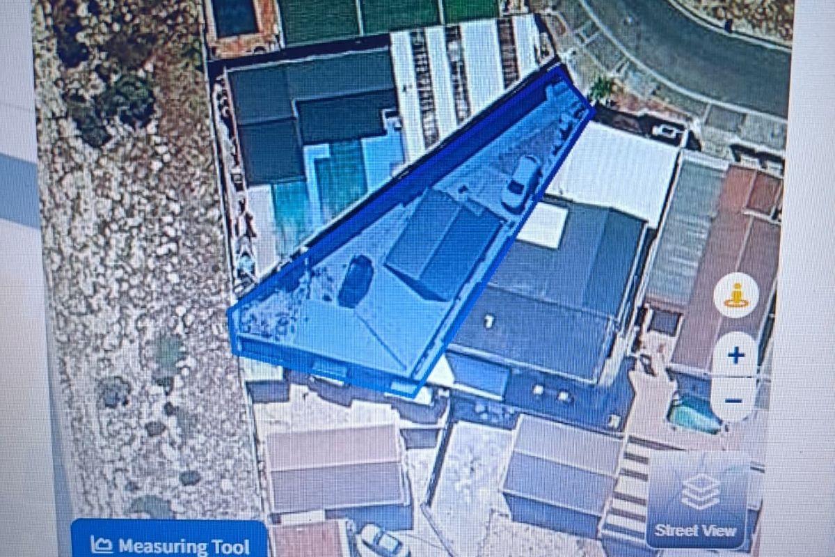 An aerial satellite view of the property showing the roof layout, swimming pool, and driveway access.