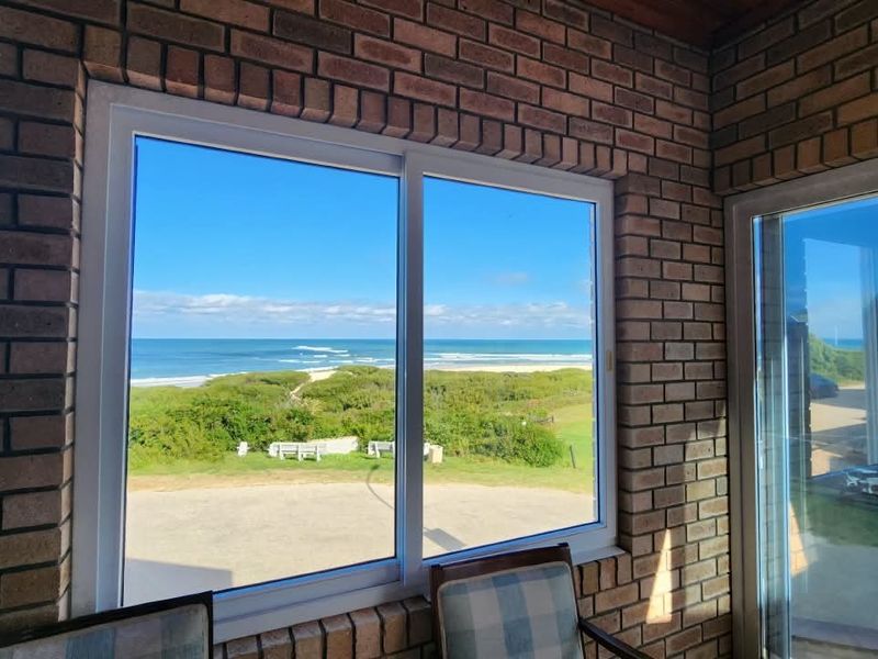Enclosed patio area featuring exposed brick walls and large sliding windows offering expansive ocean and coastal views.