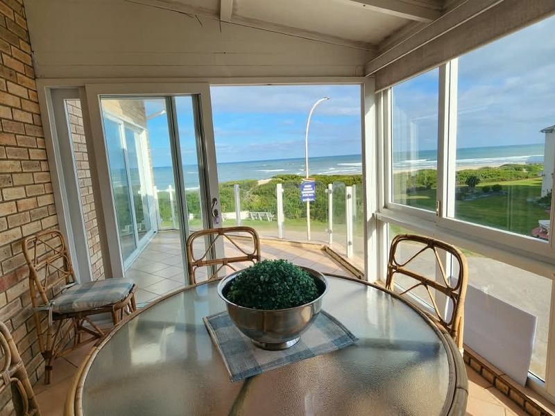 Enclosed patio area featuring exposed brickwork, tiled floors, and expansive glass windows offering panoramic ocean views.