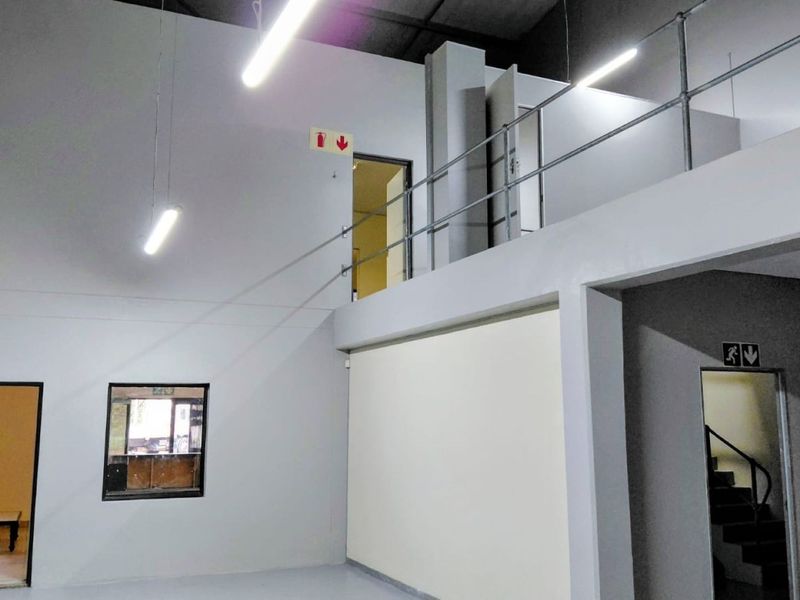 Spacious industrial utility area featuring a mezzanine level with safety railings, high ceilings, and functional internal access points.