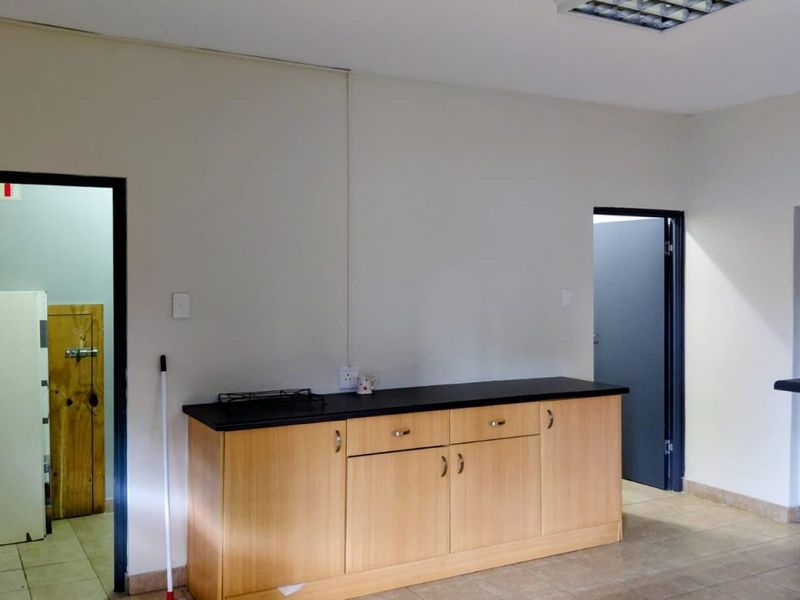 A functional kitchen area featuring light wood-finish cabinetry, a dark laminate countertop, and tiled flooring, providing a clean and practical workspace.