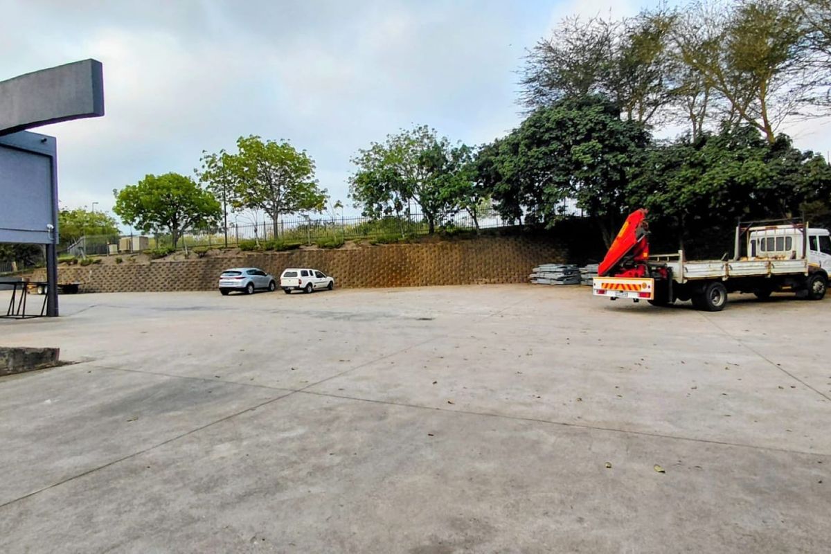 Spacious industrial concrete yard featuring a retaining wall and perimeter fencing, suitable for vehicle access and storage.