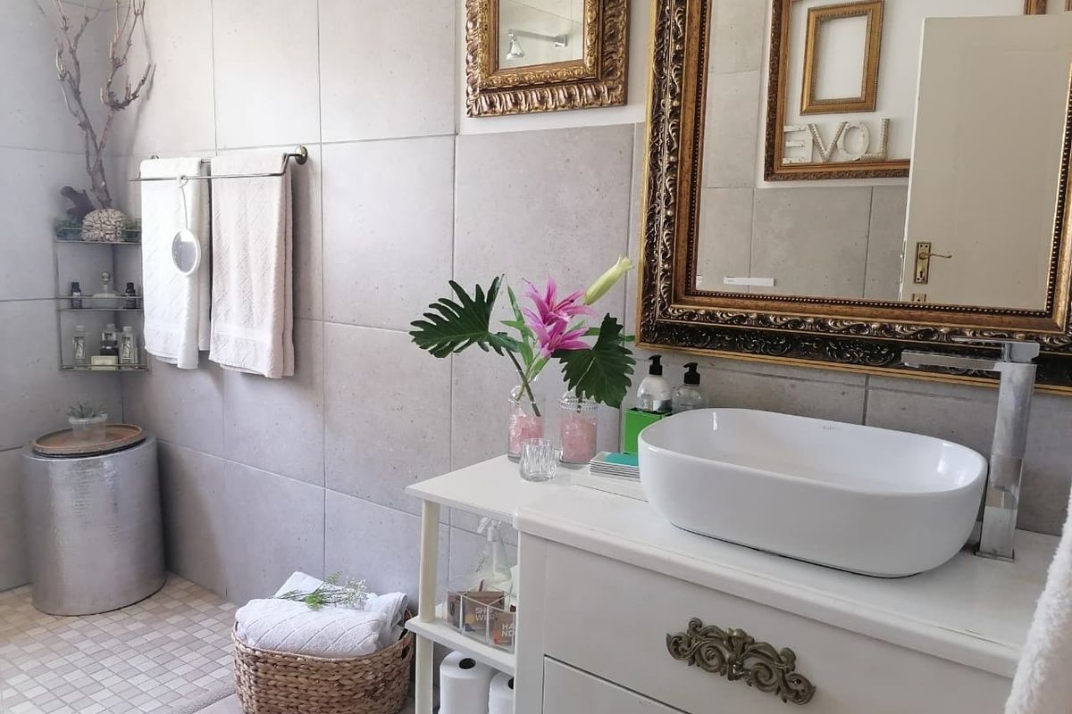 A modern bathroom featuring a white vanity cabinet with a vessel sink, contemporary wall tiling, and a sleek mixer tap.