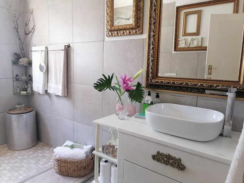 A modern bathroom featuring a white vanity cabinet with a vessel sink, contemporary wall tiling, and a sleek mixer tap.