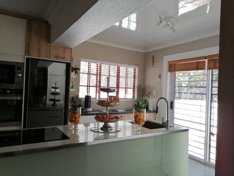 Modern kitchen featuring a central island with an undermount sink, built-in appliances, sleek cabinetry, and direct access to the outdoor area via sliding doors.