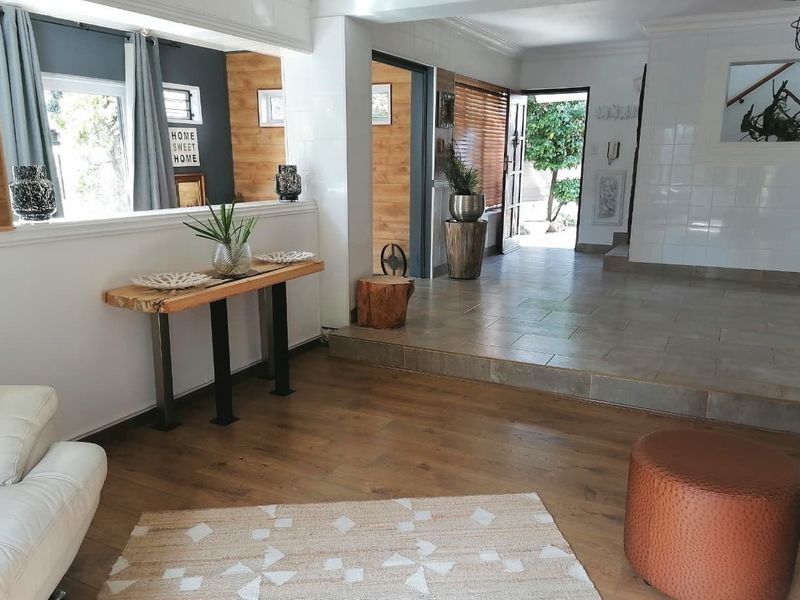 Spacious entrance hall featuring a mix of tiled and timber laminate flooring, with a raised transition area and timber wall accents.