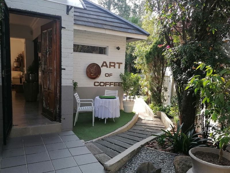 A charming outdoor patio area featuring a stone pathway, artificial grass, and direct access to the interior through a wooden door.