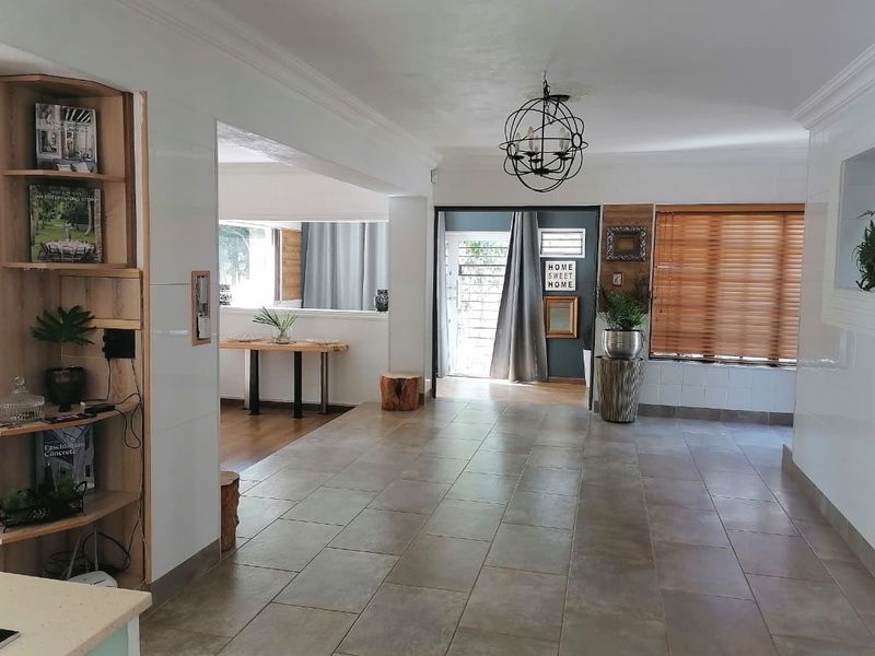 Spacious open-plan living area featuring neutral tiled flooring, built-in shelving, and natural light through venetian blinds.