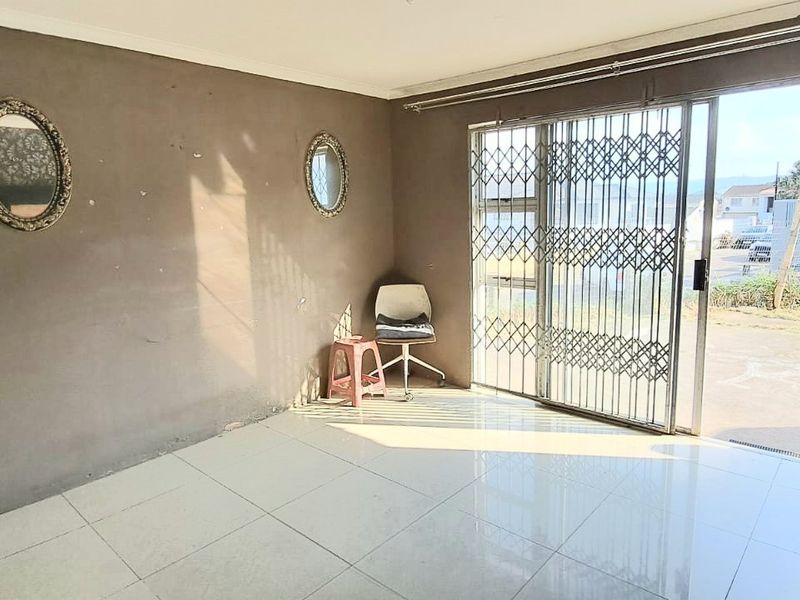 A bright, open living area featuring large sliding glass doors with security gates, tiled flooring, and neutral wall finishes.