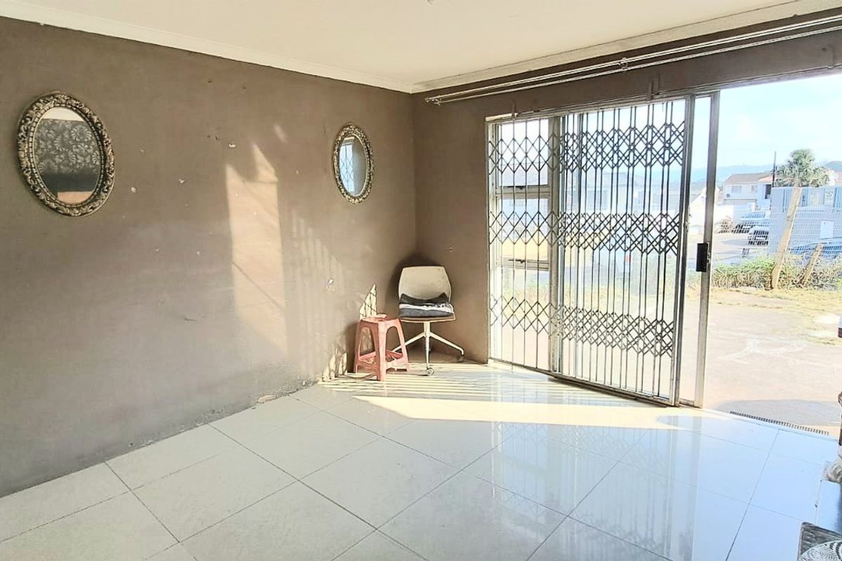 A bright, open living area featuring large sliding glass doors with security gates, tiled flooring, and neutral wall finishes.