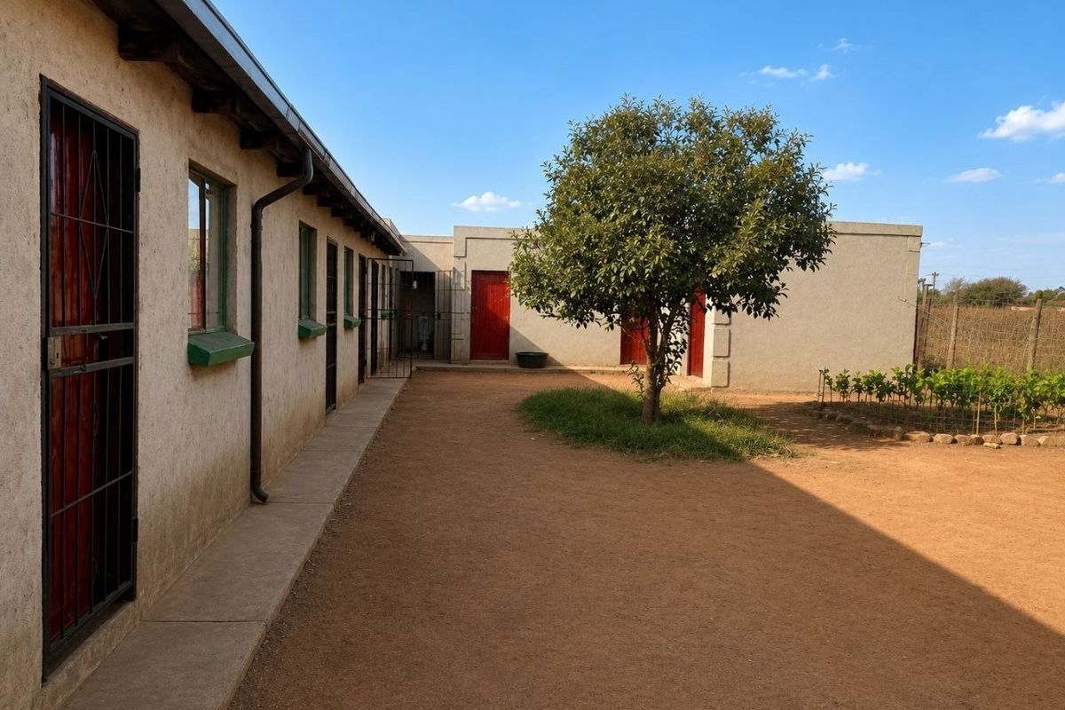 Rear courtyard area featuring a concrete pathway, multiple access points with security gates, and a central tree in a natural earth yard.