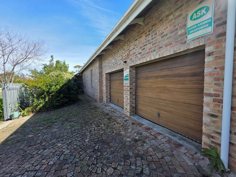 Exterior view of a double garage with brick facade and cobblestone driveway.