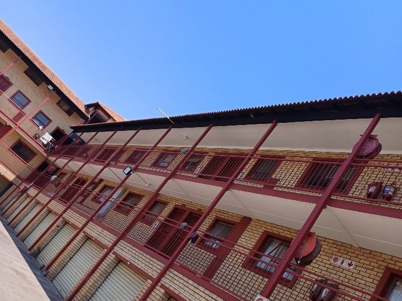 Exterior view of a multi-story apartment complex featuring face brick construction, metal security gates, and external fire safety equipment.
