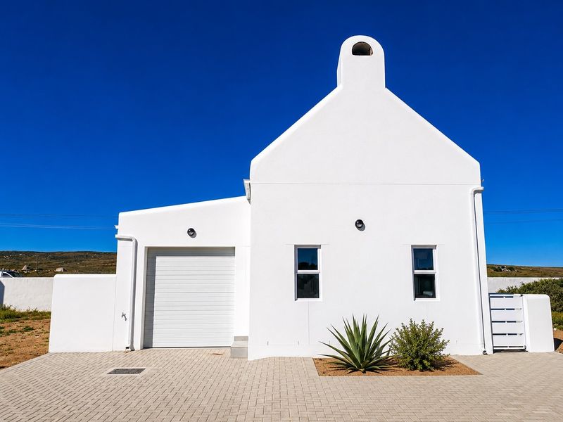 A clean, modern white house exterior featuring a paved driveway, integrated garage, and a prominent chimney against a clear blue sky.