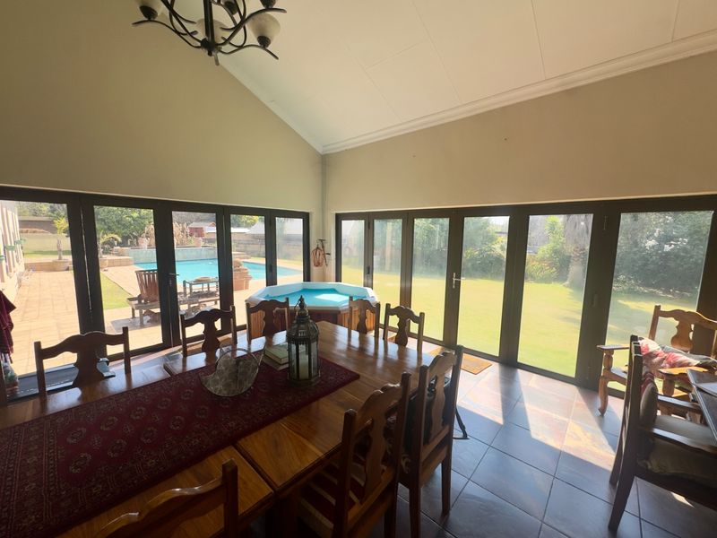 Spacious open-plan living area featuring vaulted ceilings, tiled floors, and extensive bi-fold doors providing seamless access to the pool area and garden.