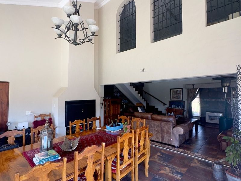 Spacious open-plan dining and living area featuring high vaulted ceilings, slate tile flooring, and a prominent built-in fireplace with arched windows.