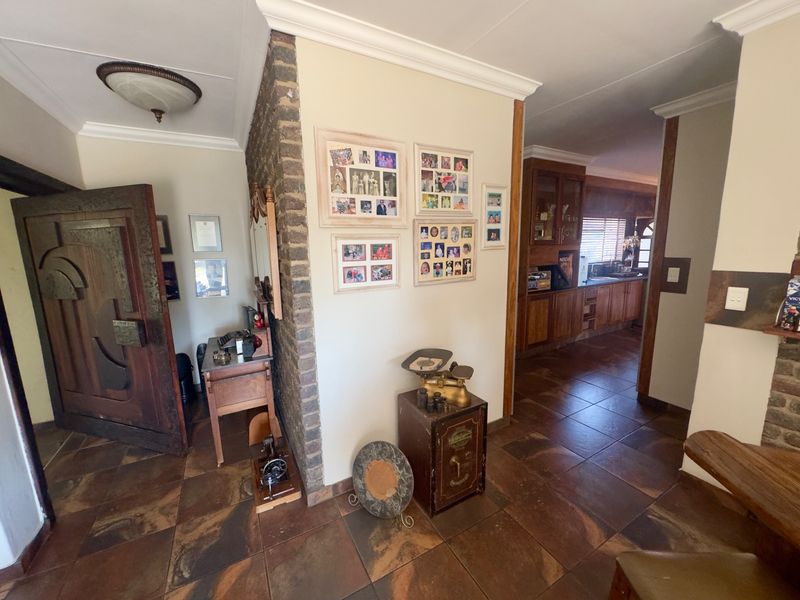 Entrance foyer featuring tiled flooring, an exposed brick feature pillar, and a solid wood front door, leading through to the kitchen area.