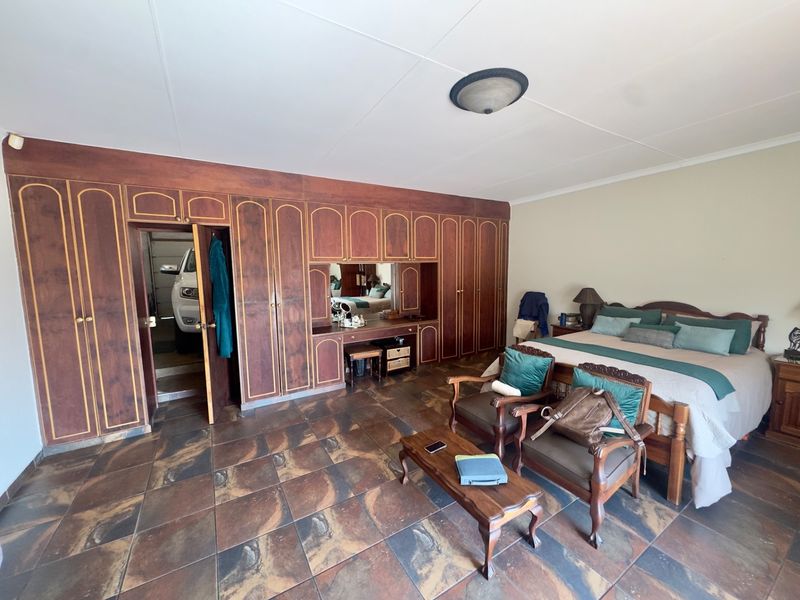 Spacious bedroom featuring extensive built-in wooden cabinetry with an integrated vanity and durable tiled flooring.