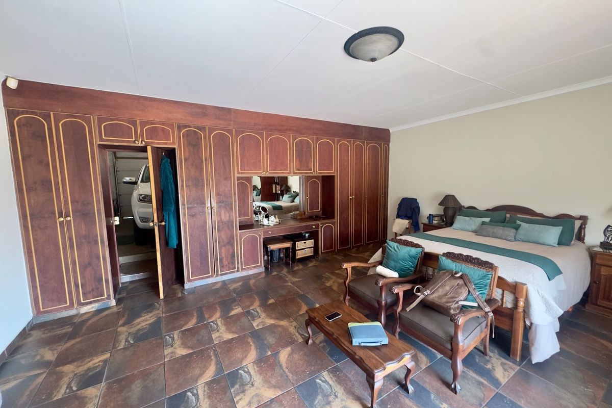 Spacious bedroom featuring extensive built-in wooden cabinetry with an integrated vanity and durable tiled flooring.