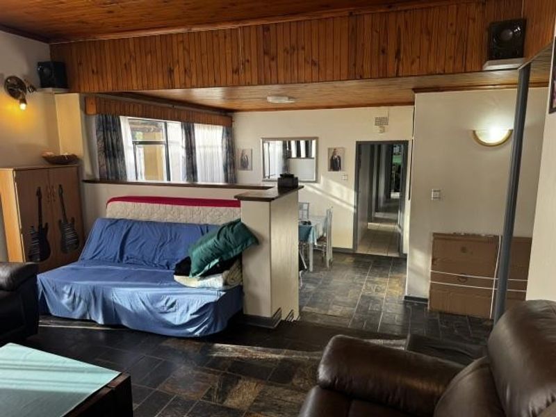 Open plan living area featuring slate tile flooring and a timber tongue and groove ceiling with a central partition wall.