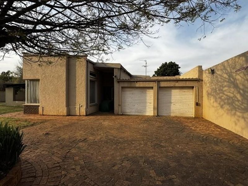 Front view of the property featuring a double garage with roller shutter doors and a paved driveway area.