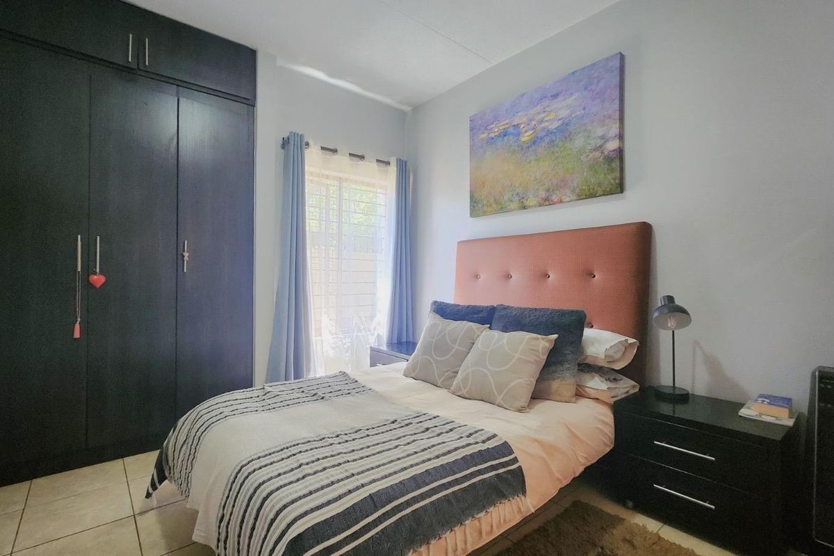 A well-maintained bedroom featuring dark built-in cupboards and neutral tiled flooring, offering a functional and comfortable living space.