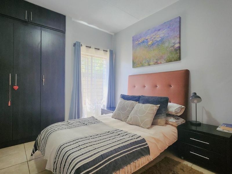 A well-maintained bedroom featuring dark built-in cupboards and neutral tiled flooring, offering a functional and comfortable living space.