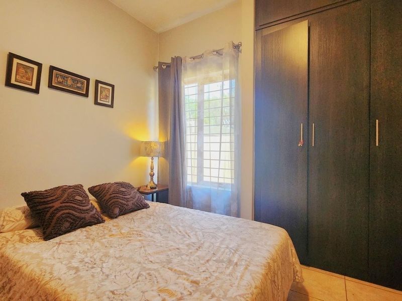 A cozy bedroom featuring a large built-in wardrobe and a window fitted with security bars, providing functional storage and natural light.
