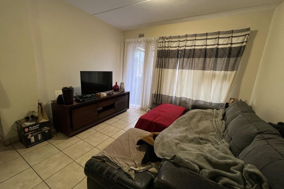 A living room featuring ceramic floor tiles and a sliding glass door providing access to an outdoor area.