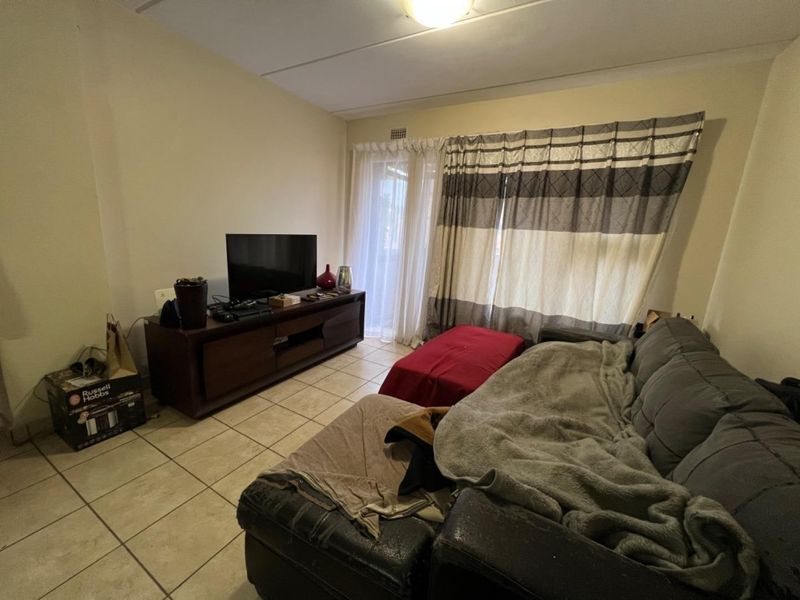 A living room featuring ceramic floor tiles and a sliding glass door providing access to an outdoor area.