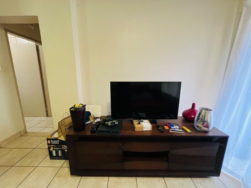 A living room area featuring neutral wall finishes and tiled flooring, providing a functional space for entertainment.
