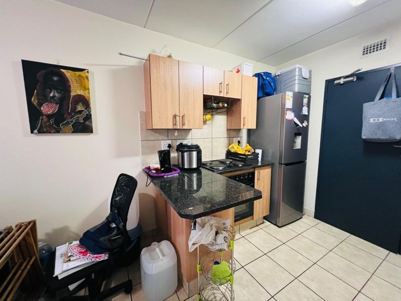 Compact kitchen featuring granite countertops, built-in cabinetry, and tiled flooring, providing a functional workspace within the apartment.