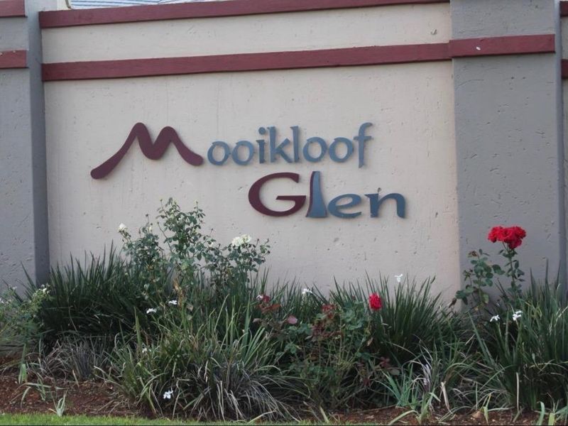 A view of the Mooikloof Glen estate entrance signage mounted on a solid boundary wall with landscaped garden beds.
