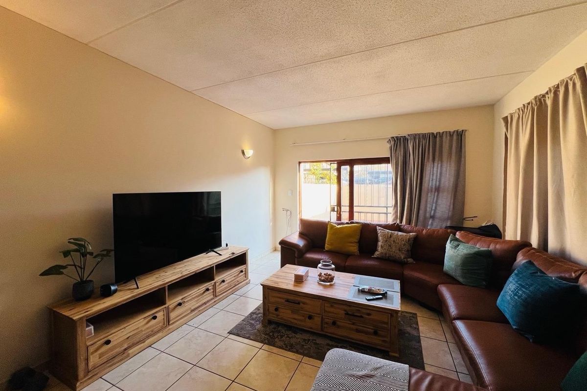 A comfortable living room featuring tiled flooring and a sliding glass door providing access to the exterior.