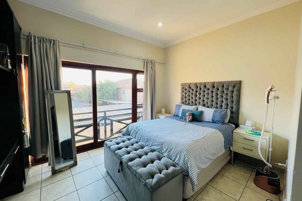 A well-lit bedroom featuring tiled flooring, coved ceilings, and a large sliding glass door providing access to an outdoor balcony area.