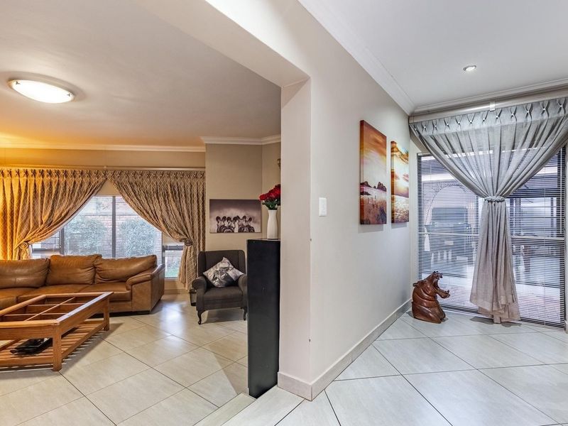 An open-plan living area featuring neutral tiled flooring, recessed lighting, and large windows with sliding glass doors providing access to the exterior.