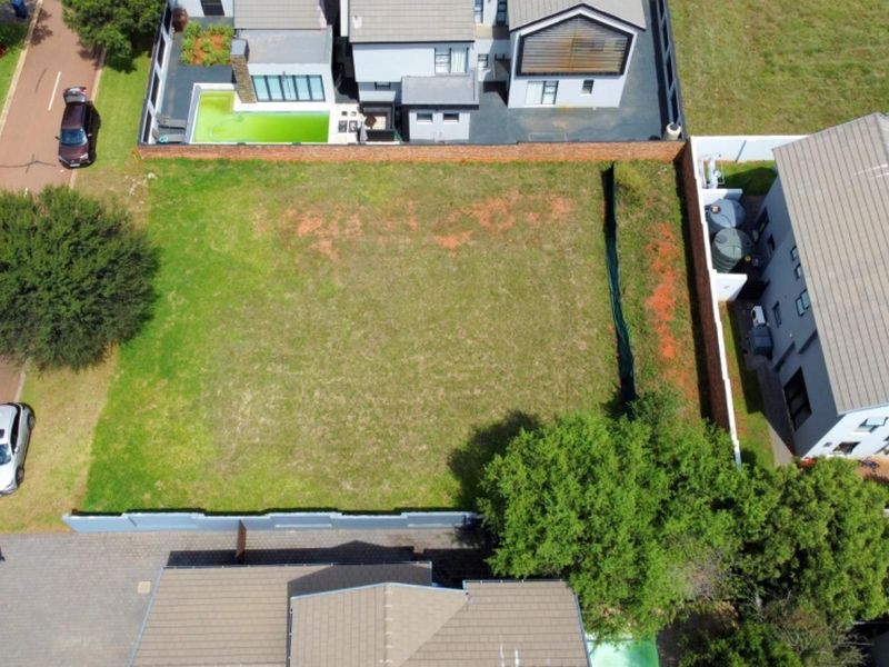 Aerial view of a vacant residential plot situated within a developed estate, featuring established boundary walls and surrounding residential properties.
