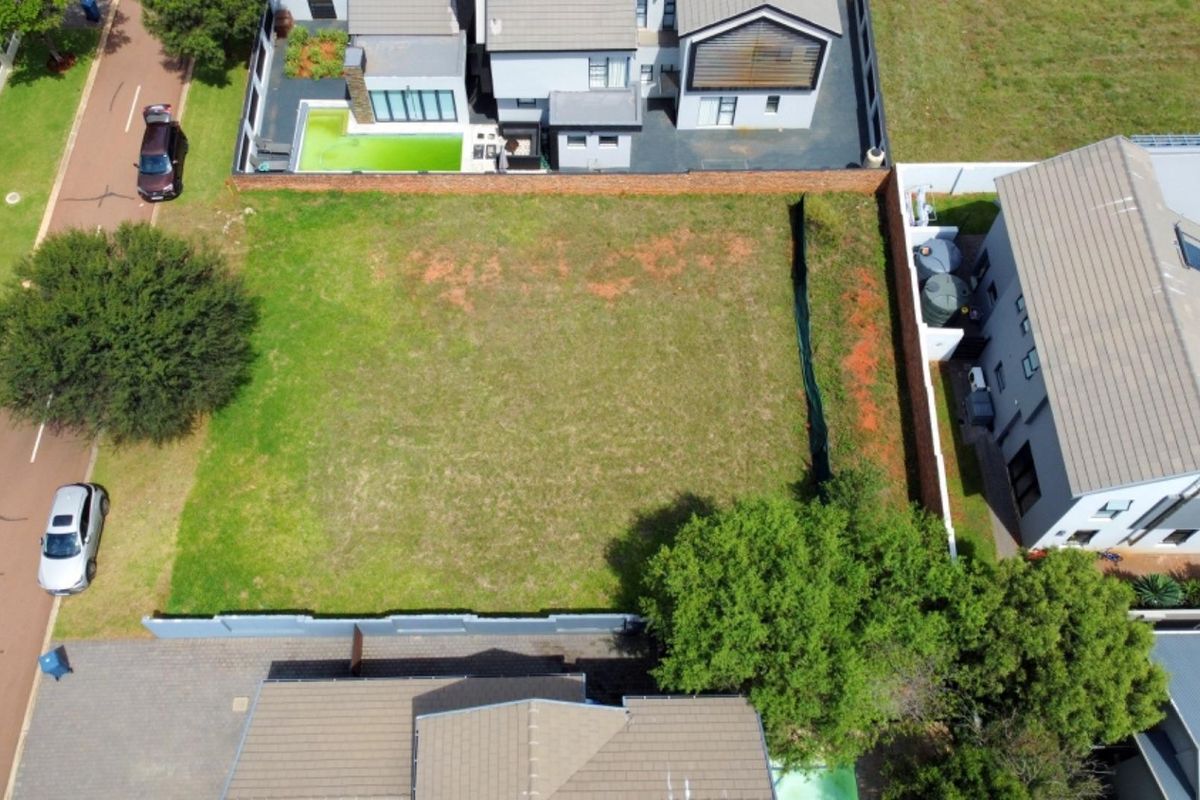 Aerial view of a vacant residential plot situated within a developed estate, featuring established boundary walls and surrounding residential properties.
