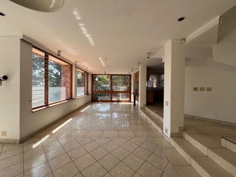 Spacious open-plan living area featuring large windows, tiled flooring, and a split-level layout, offering a bright and versatile space for modern living.