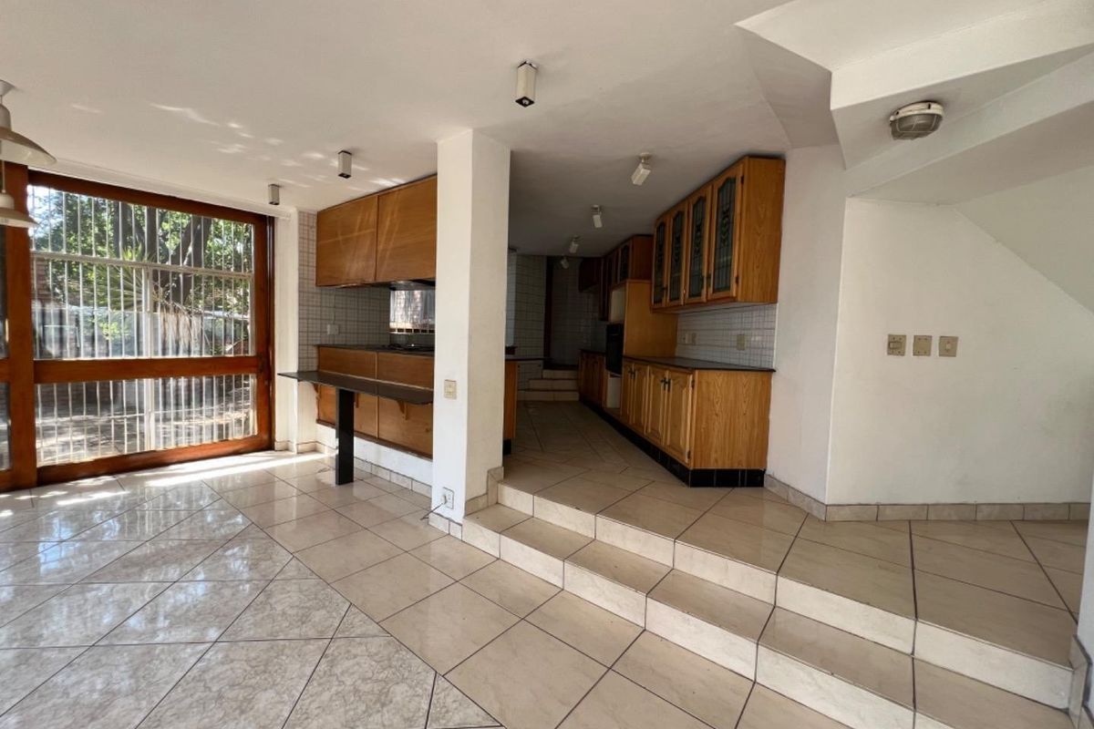 Spacious kitchen area featuring built-in wooden cabinetry, tiled flooring, and a raised platform, offering a functional layout ready for modern updates.