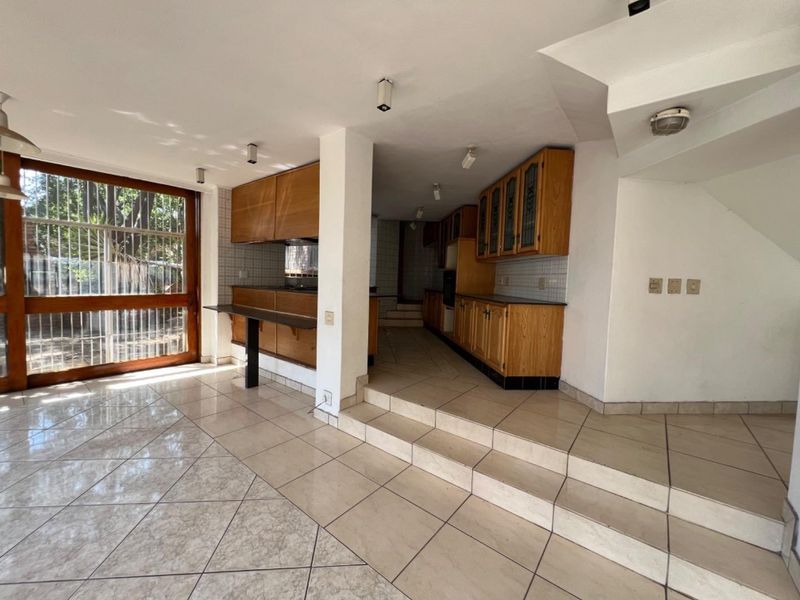 Spacious kitchen area featuring built-in wooden cabinetry, tiled flooring, and a raised platform, offering a functional layout ready for modern updates.
