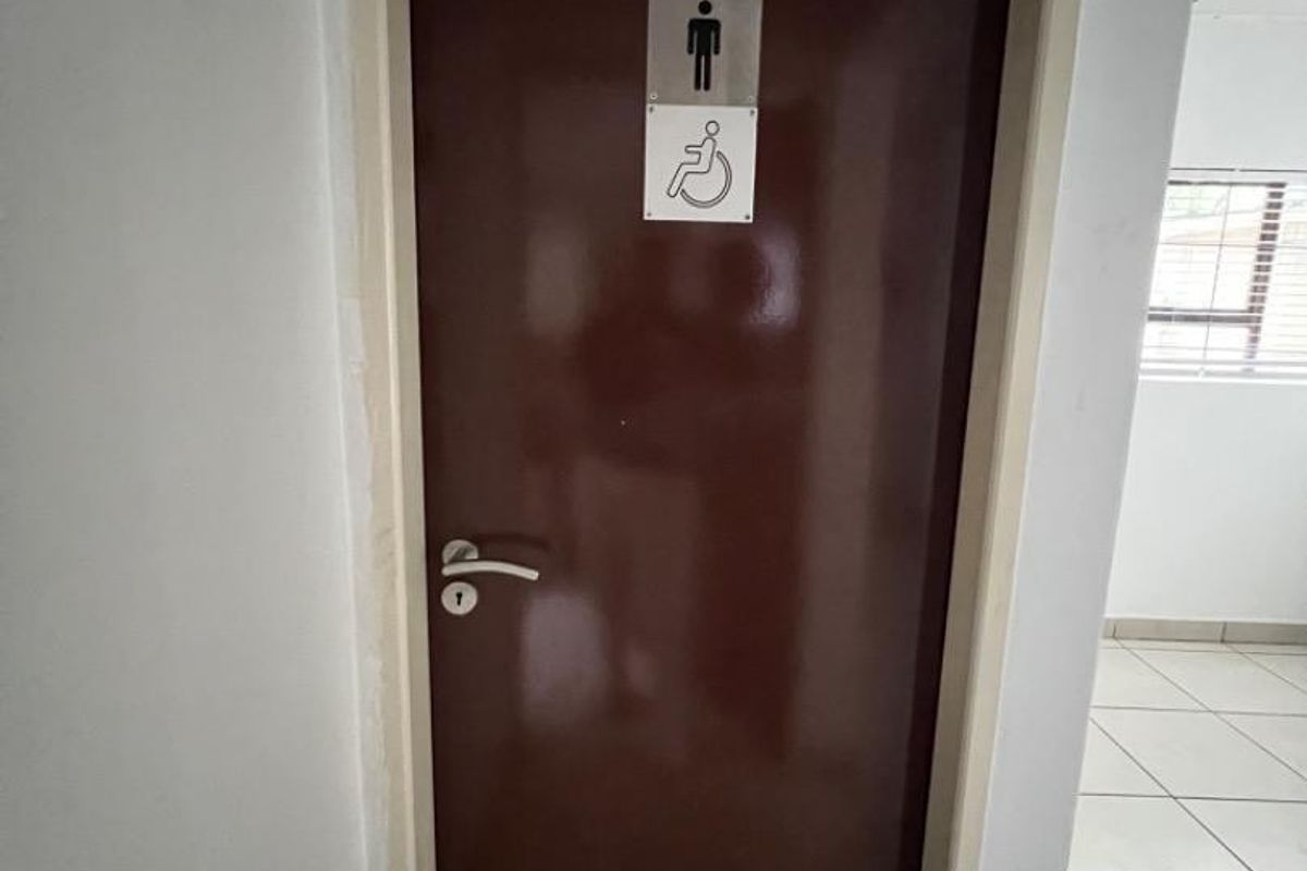 An accessible restroom door featuring signage for disabled access, set within a commercial hallway with tiled flooring.