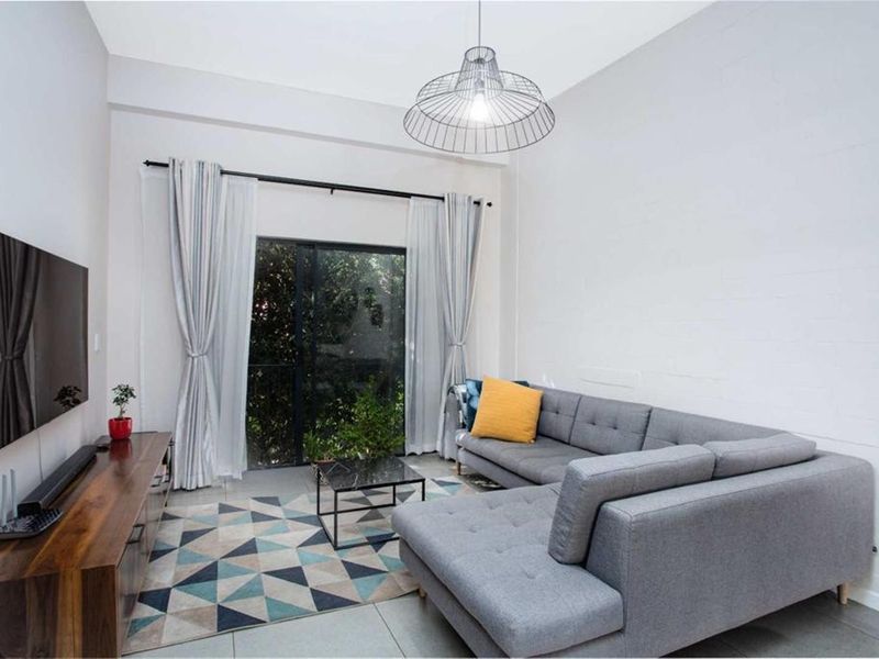 A bright living room featuring tiled flooring, a modern pendant light, and a sliding glass door providing access to an outdoor area.