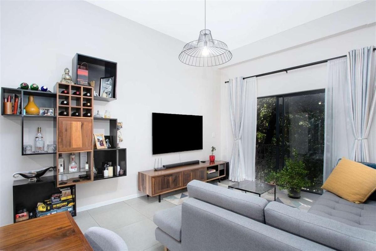 A bright and modern living room featuring tiled flooring, a large sliding glass door providing natural light, and a contemporary pendant light fixture.