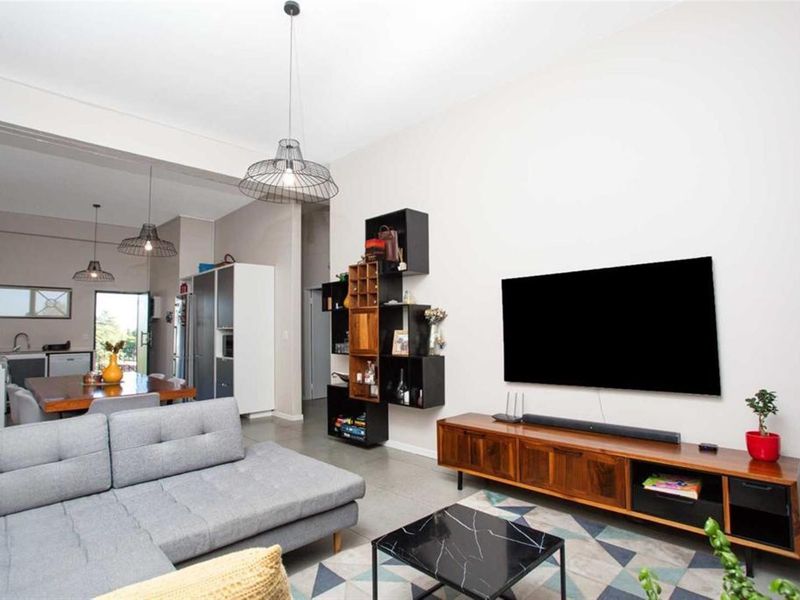 An open-plan living and dining area featuring tiled floors, modern pendant lighting, and a seamless flow into the adjacent kitchen space.