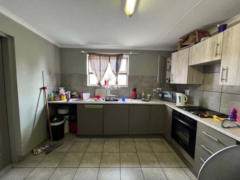 Functional kitchen featuring built-in cabinetry, laminate countertops, tiled backsplash, and integrated oven and hob, providing a practical workspace for daily use.